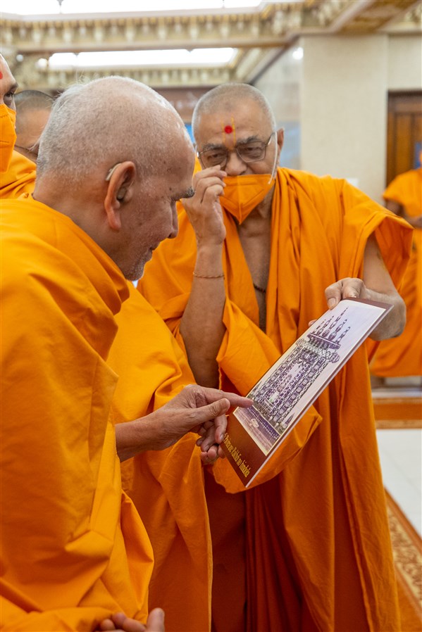 Swamishri observes an old photo of a hindolo he had created in Mumbai