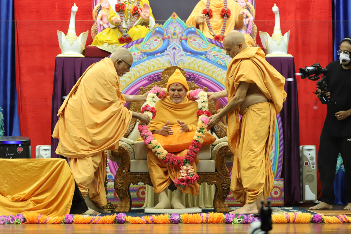 Pujya Kothari Swami and Pujya Viveksagar Swami honor Swamishri with a garland