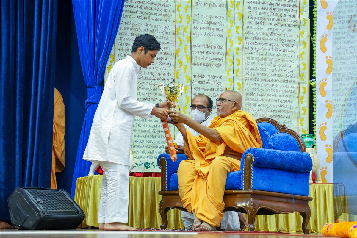 Pujya Kothari Swami presents a trophy to a youth
