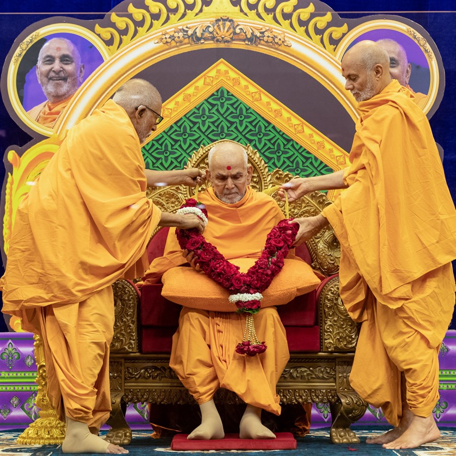 Pujya Bhaktipriya Swami (Kothari Swami) and Pujya Viveksagar Swami honor Swamishri with a garland