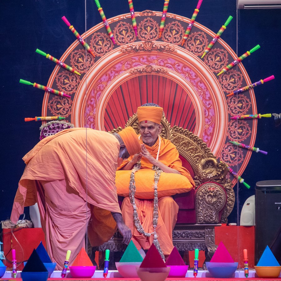 Abhayswarup Swami honors Swamishri with a garland