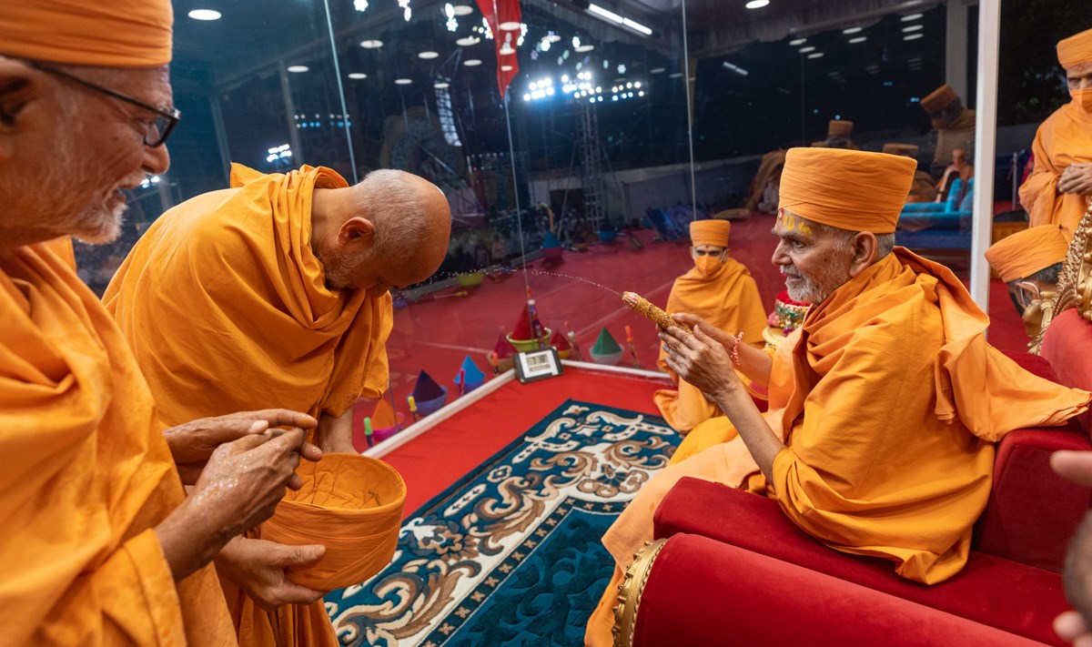 Swamishri sprays saffron-scented water on Pujya Viveksagar Swami