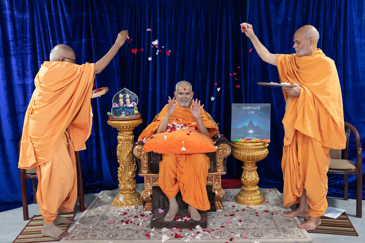 Pujya Kothari Swami and Pujya Viveksagar Swami shower flower petals on Swamishri