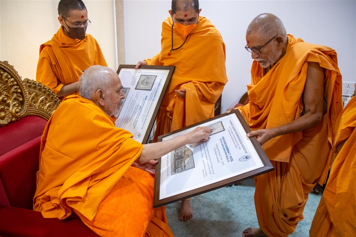 Swamishri sanctifies a certificate presented to Pujya Bhaktipriya Swami (Kothari Swami)