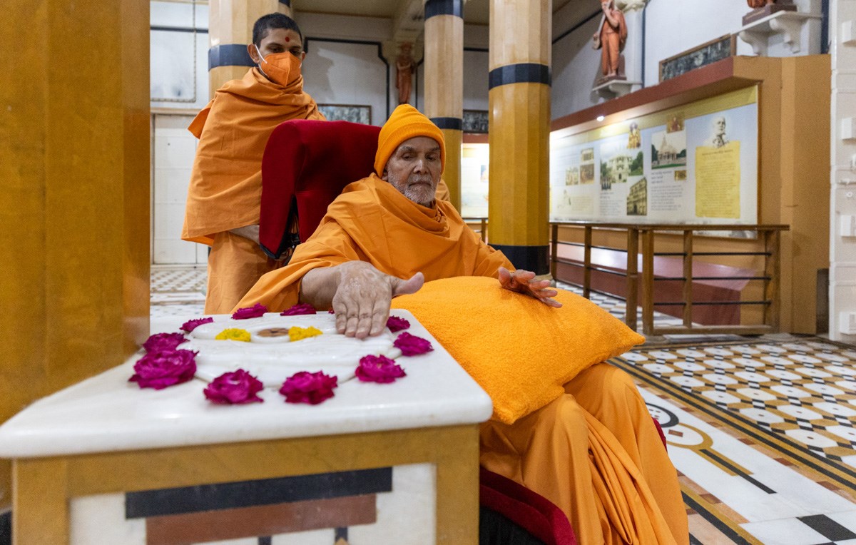Swamishri engrossed in darshan of the holy charanarvind of Bhagwan Swaminarayan in the Rang Mandap