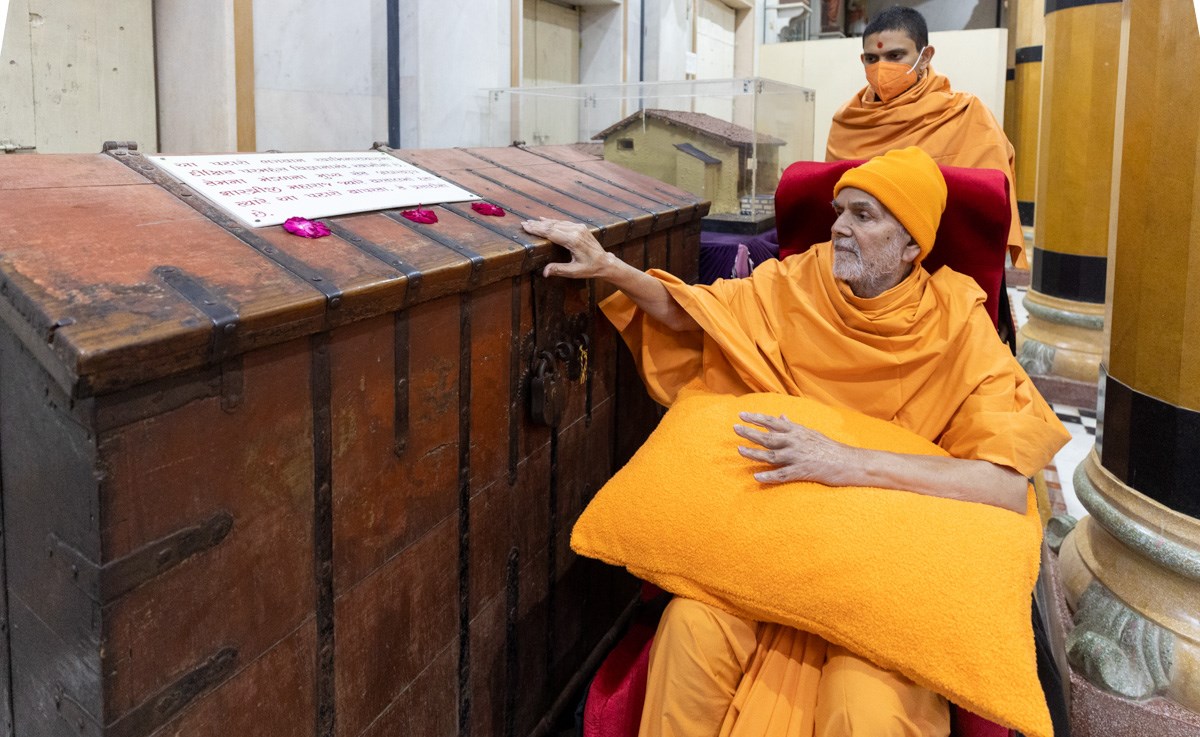 Swamishri engrossed in the darshan of a wooden storage chest sanctified by Brahmaswarup Shastriji Maharaj
