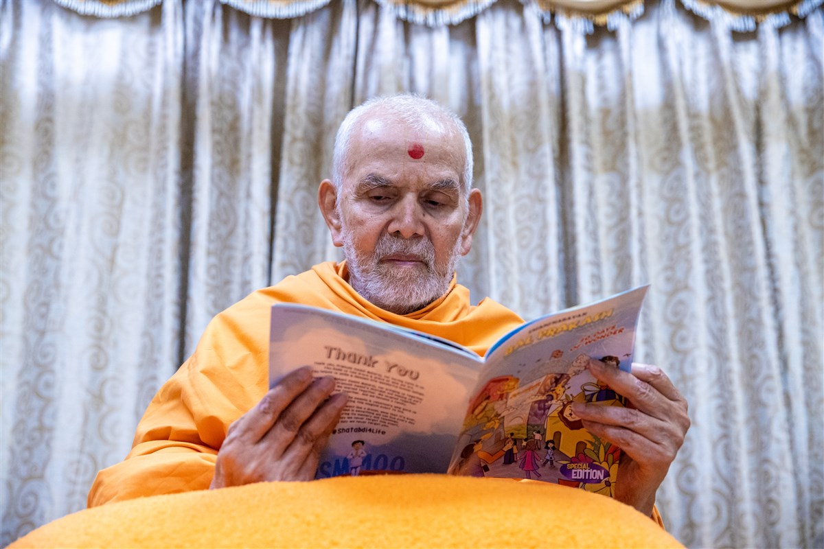 Swamishri reads the latest English issue of 'Swaminarayan Bal Prakash'