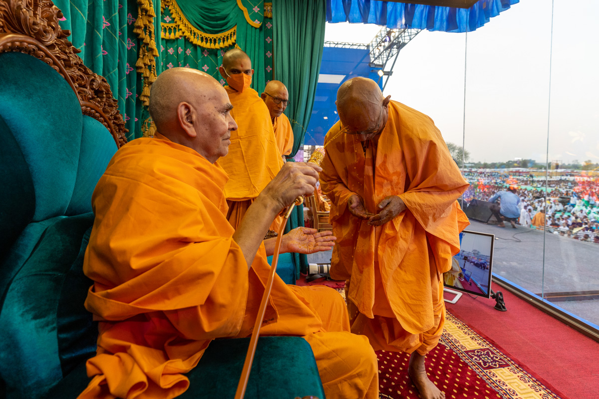 Swamishri sprays saffron-scented water on Pujya Doctor Swami