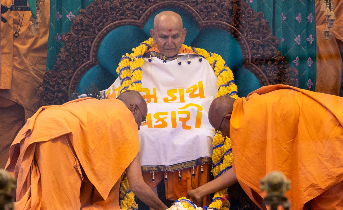 Gnaneshwar Swami and Narayanmuni Swami honor Swamishri with a shawl and a garland