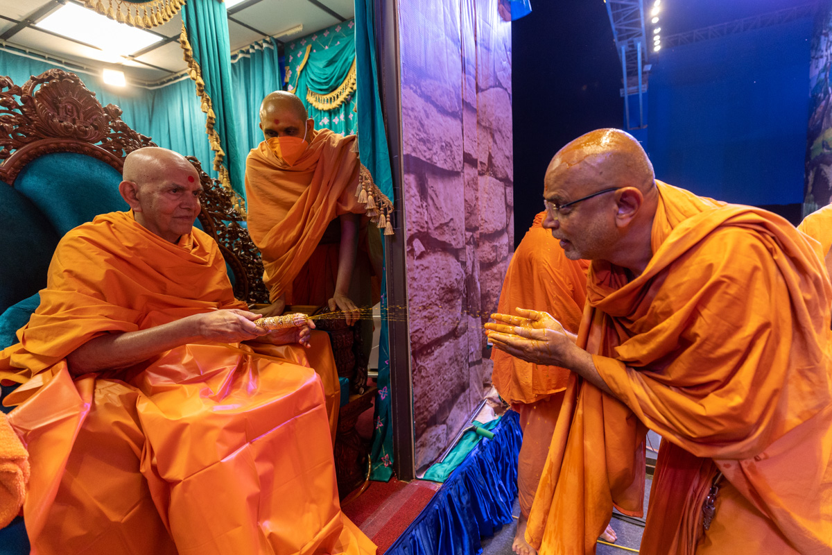 Swamishri sprays sanctified saffron-scented water on Gnaneshwar Swami