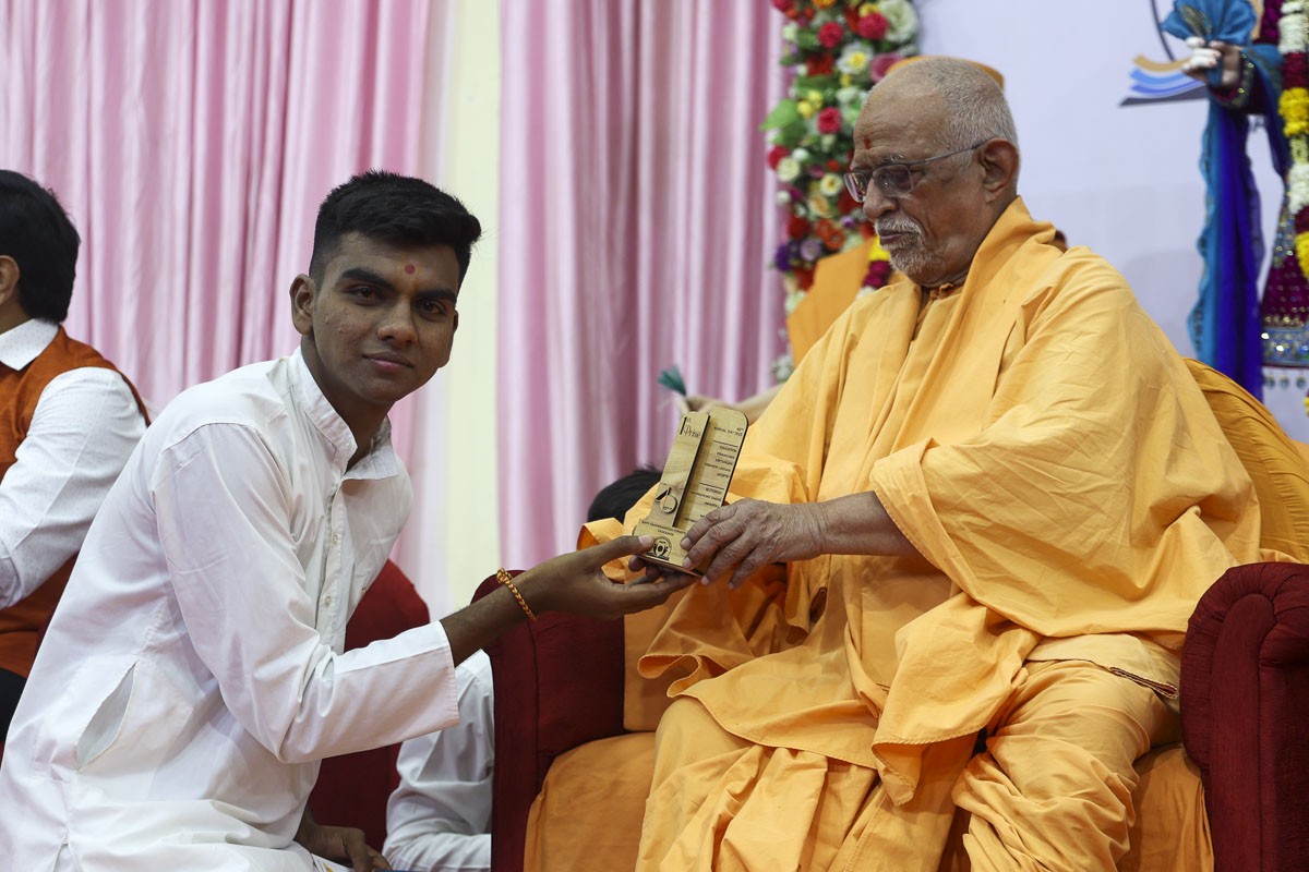 Pujya Doctor Swami presents a trophy to a youth