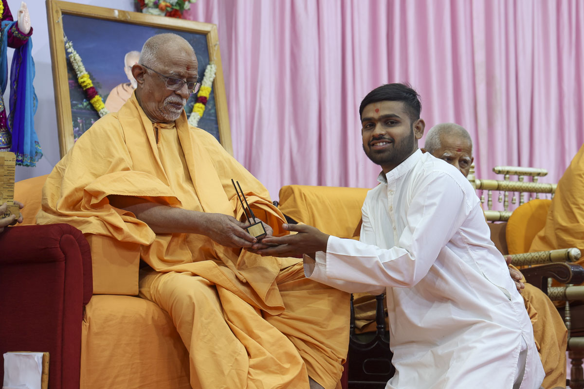 Pujya Doctor Swami presents a trophy to a youth