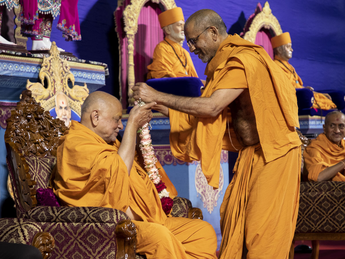 Shrinivas Swami honors Pujya Ishwarcharan Swami with a garland