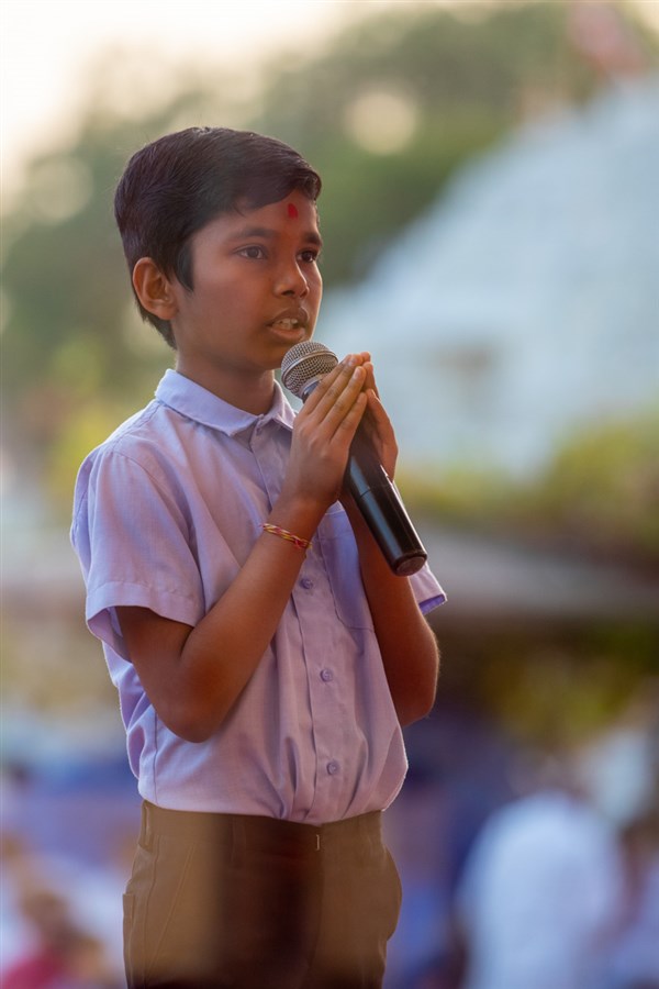 A student recites scriptural passages in Swamishri's puja