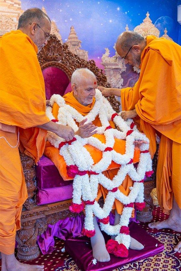 Gnaneshwar Swami and Narayanmuni Swami honor Swamishri with a garland