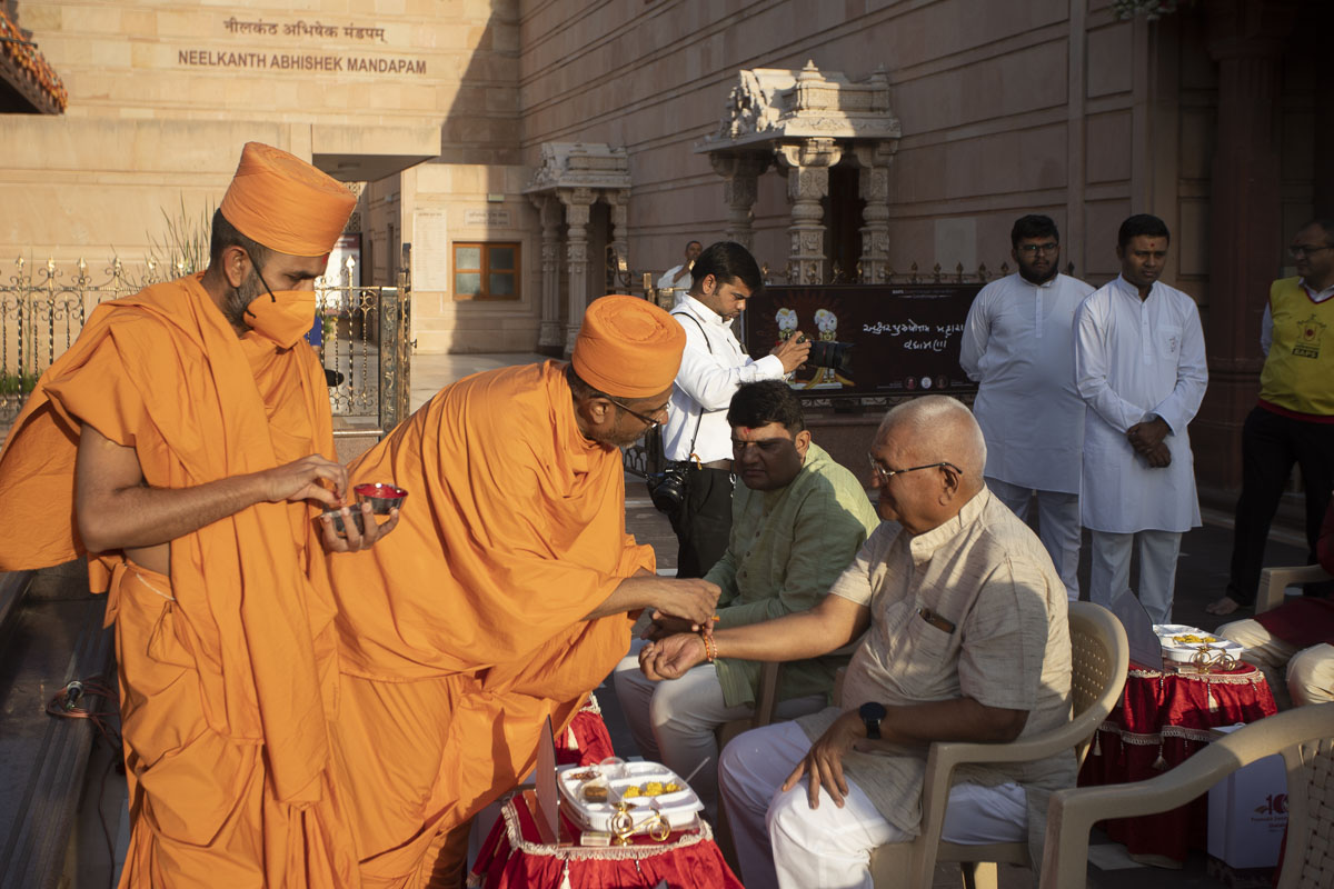 A sadhu ties a nadachhadi to a devotee