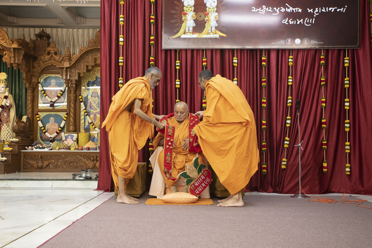 Anandswarup Swami and Vishwavihari Swami honor Pujya Ishwarcharan Swami with a garland