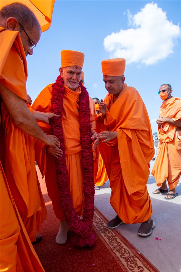 Gnaneshwar Swami and Brahmavihari Swami honor Swamishri with a garland