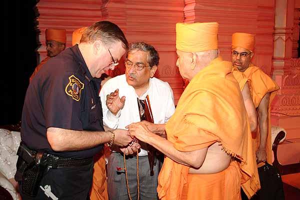 Swamishri teaches Policeman Allen Sabo how to do the mala 