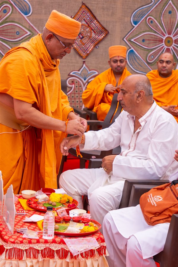A sadhu ties a nadachhadi to a devotee