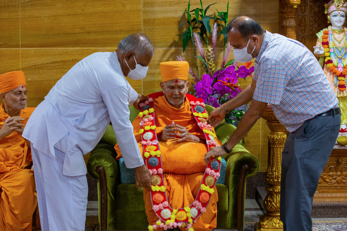 Dignitaries honor Swamishri with a garland