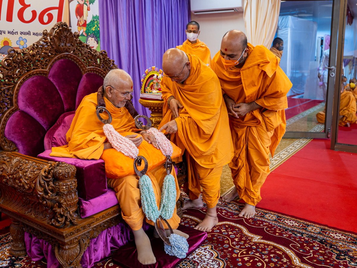 Pujya Ghanshyamcharan Swami honors Swamishri with a garland