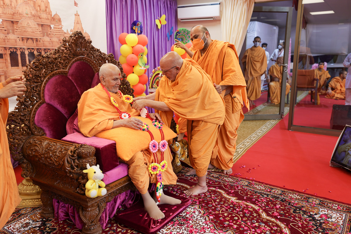 Pujya Ghanshyamcharan Swami honors Swamishri with a garland