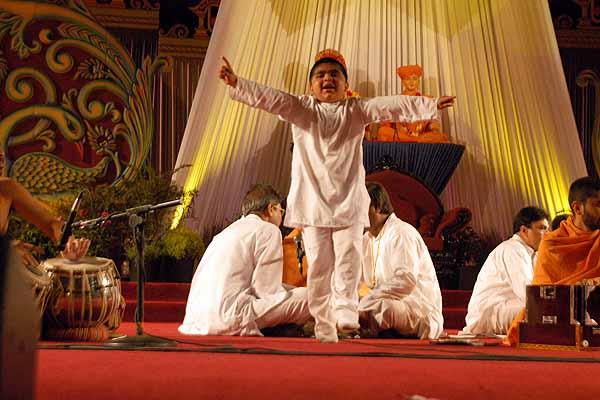 A child dances jubilantly as saints and devotees sing kirtans 
