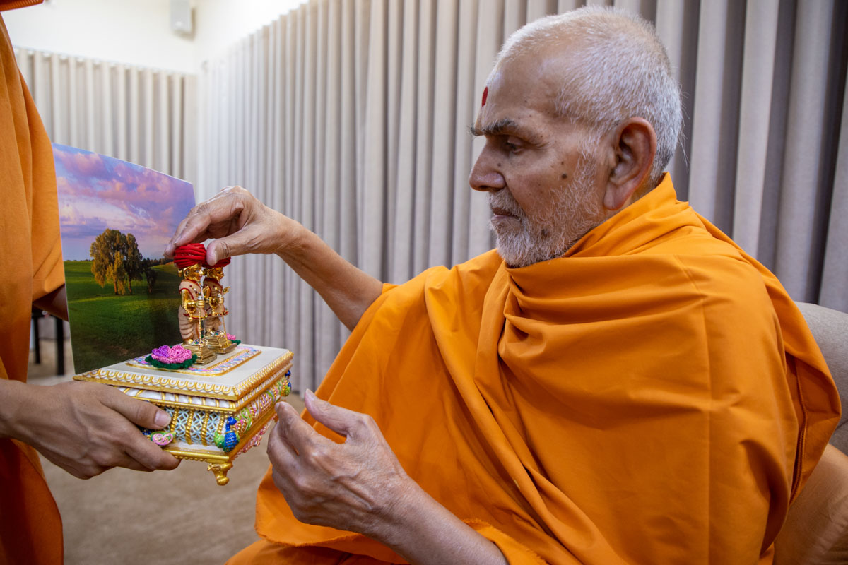 Swamishri observes chandan garments offered to Shri Harikrishna Maharaj and Shri Gunatitanand Swami
