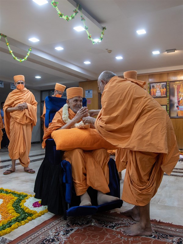 Yagnapriya Swami honors Swamishri with a garland