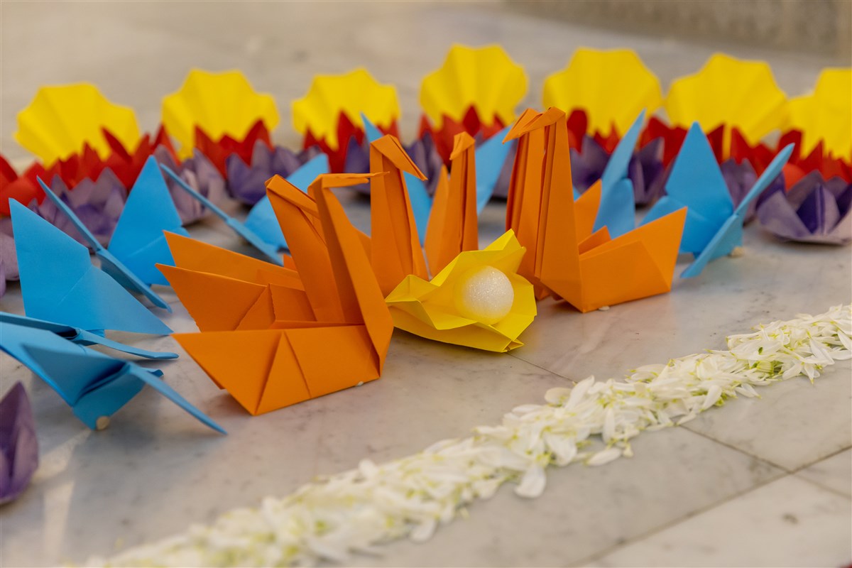 The four types of origami shapes – clams, butterflies, swans, and lotuses – depicted devotees’ pledges of seeing virtues in others, an inner transformation from seeing divinity in others, humility and service, and remaining pure amidst impurities; more than 5,500 of these shapes had been patiently hand-folded by the devotees