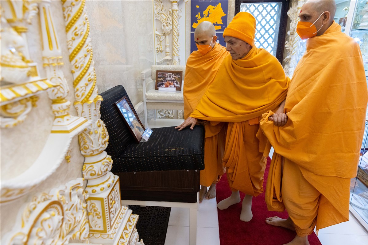 Swamishri paying his respects to the chair upon which Pramukh Swami Maharaj sat while guiding the sculptors about the murtis of London Mandir <br>(Watch <a href="https://youtu.be/tJRlBQQ60mQ?t=3259" target="blank" style="text-decoration:underline; color:blue;">here</a> to learn more)