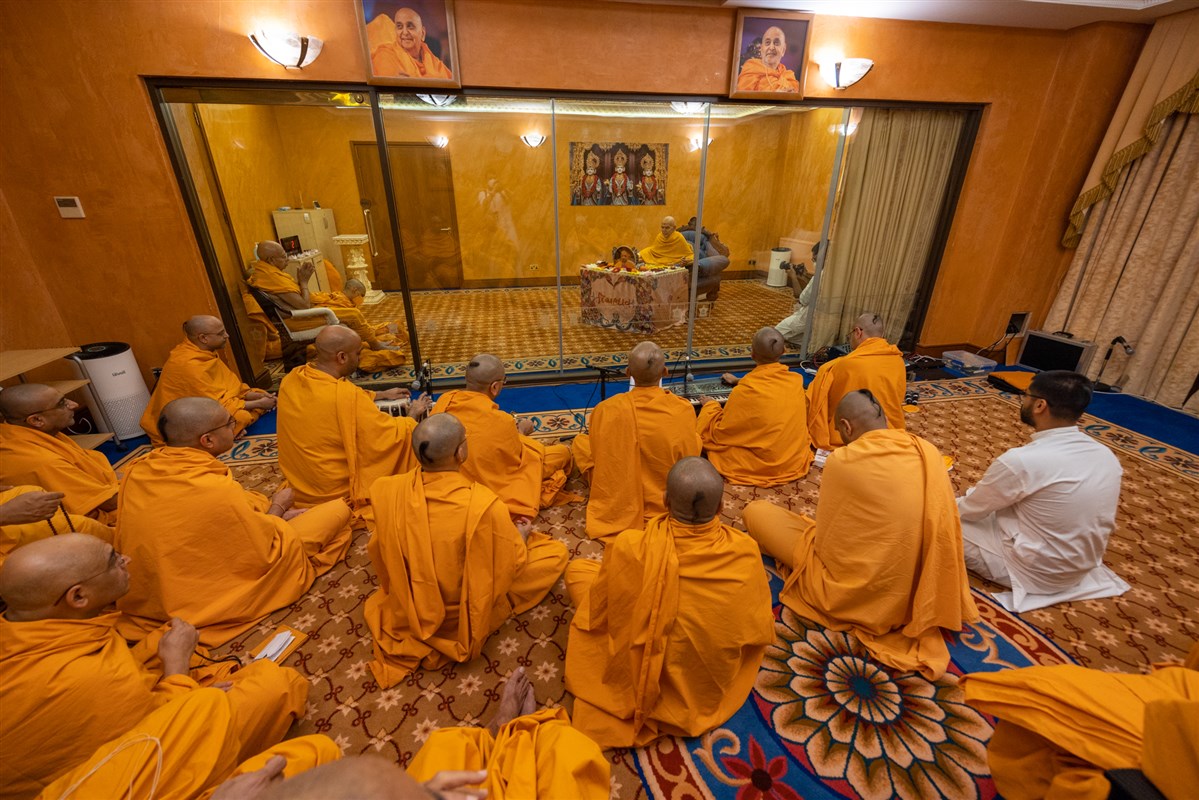 Swamis and sadhaks engrossed in Swamishri's darshan as he performs his puja