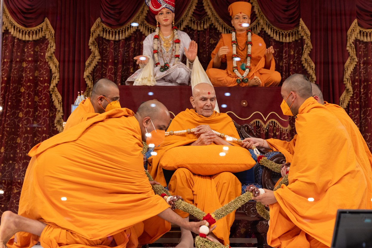 Swamis honour Swamishri with a decorative garland