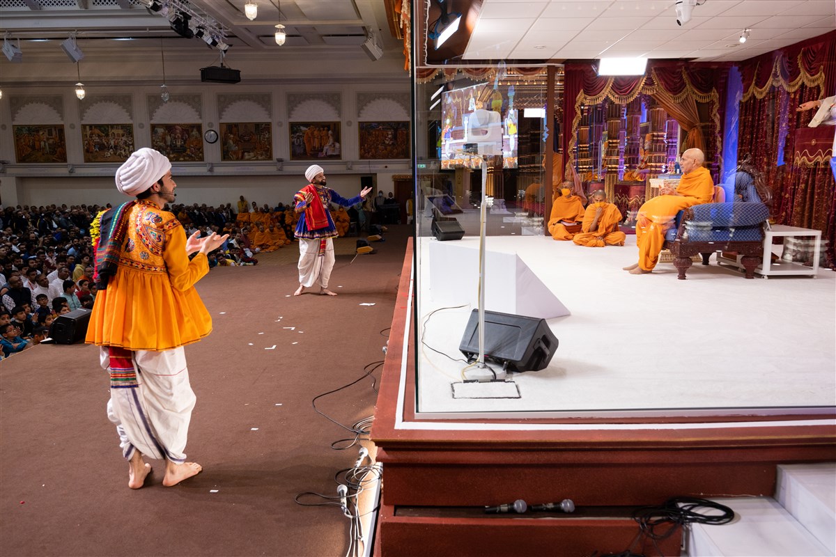 Youths narrate the spiritual significance of Swamishri's presence in the assembly along with Shri Harikrishna Maharaj and Shri Gunatitanand Swami Maharaj