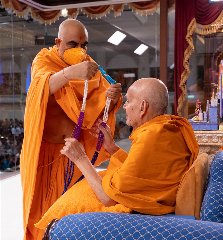 Yogvivekdas Swami honours Swamishri with a similar garland of beads