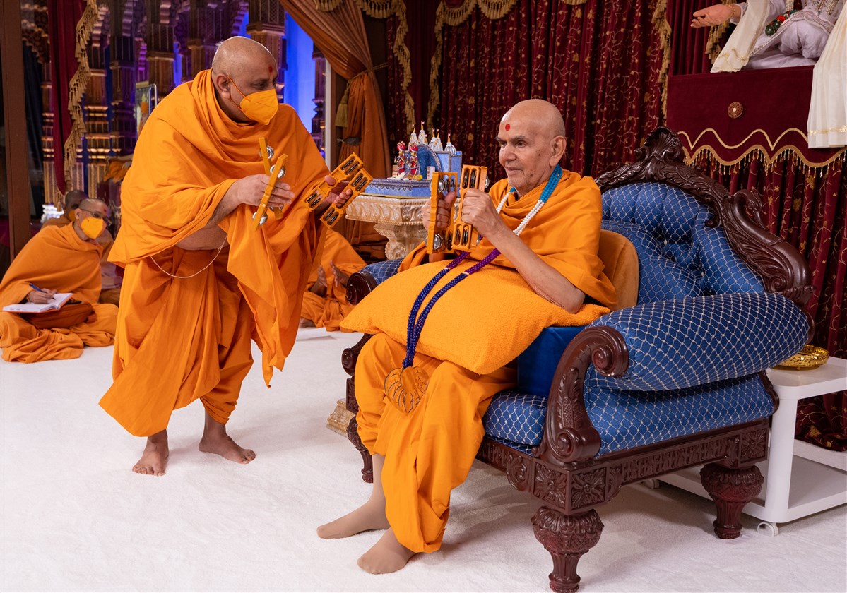Anandpriyadas Swami offers Swamishri the kartal in jubilation of the arrival of Shri Harikrishna Maharaj and Shri Gunatitanand Swami in London