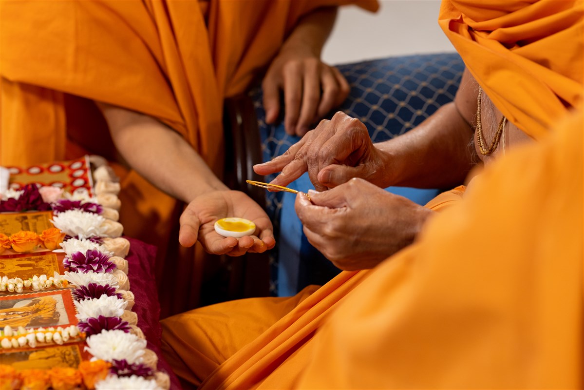 Swamishri commences his morning puja by applying sandalwood paste for a tilak