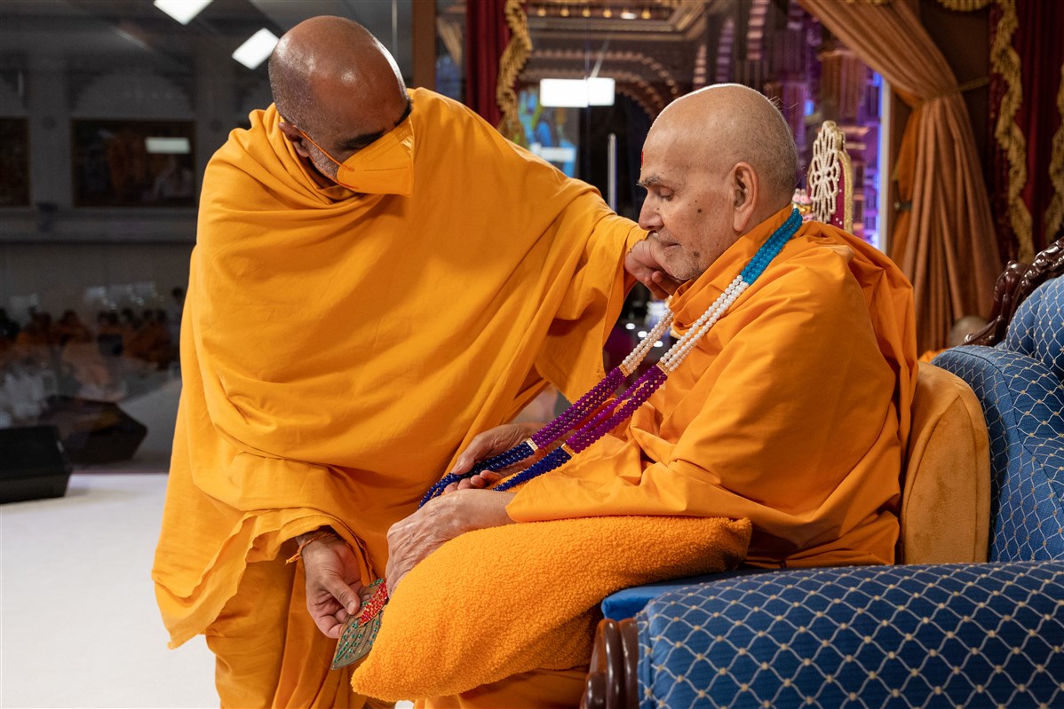 Satyavratdas Swami honours Swamishri with a garland of beads
