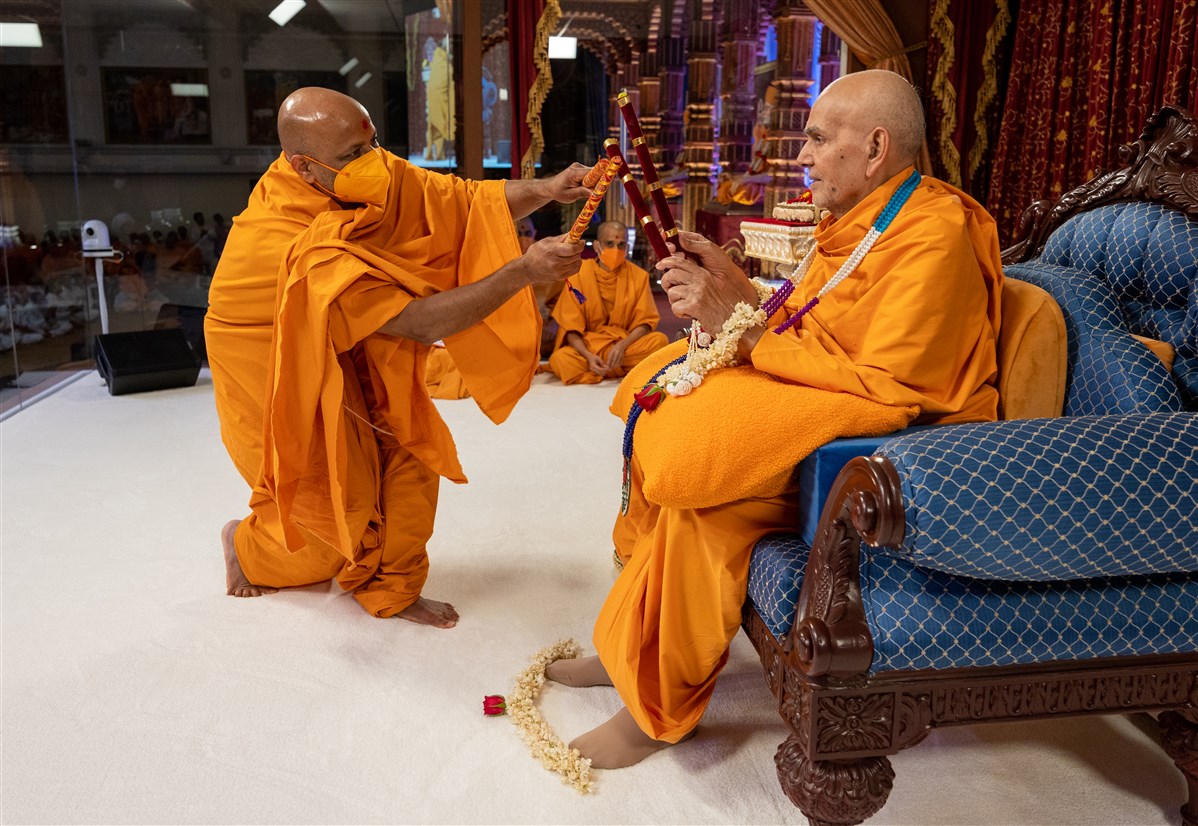 Mangaltirth Swami offers Swamishri raas sticks and plays with him