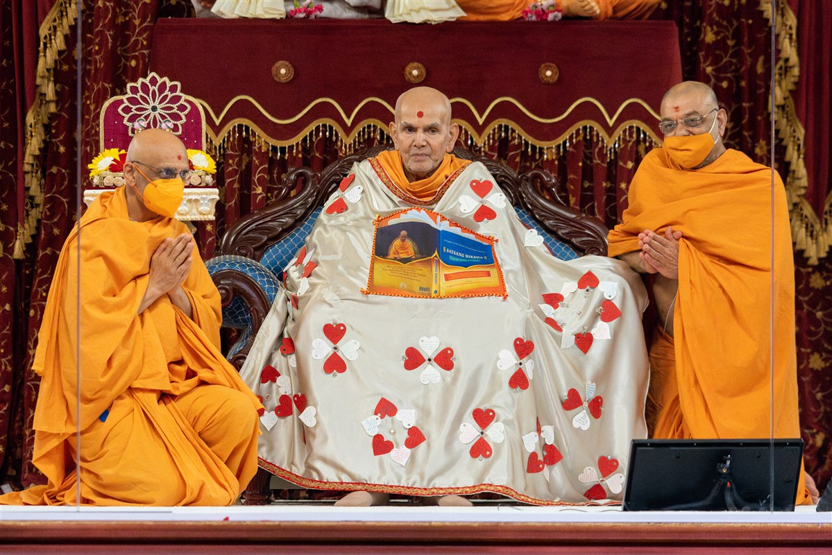 Bhaktivallabhdas Swami and Tyagprakashdas Swami offer the decorative shawl to Swamishri