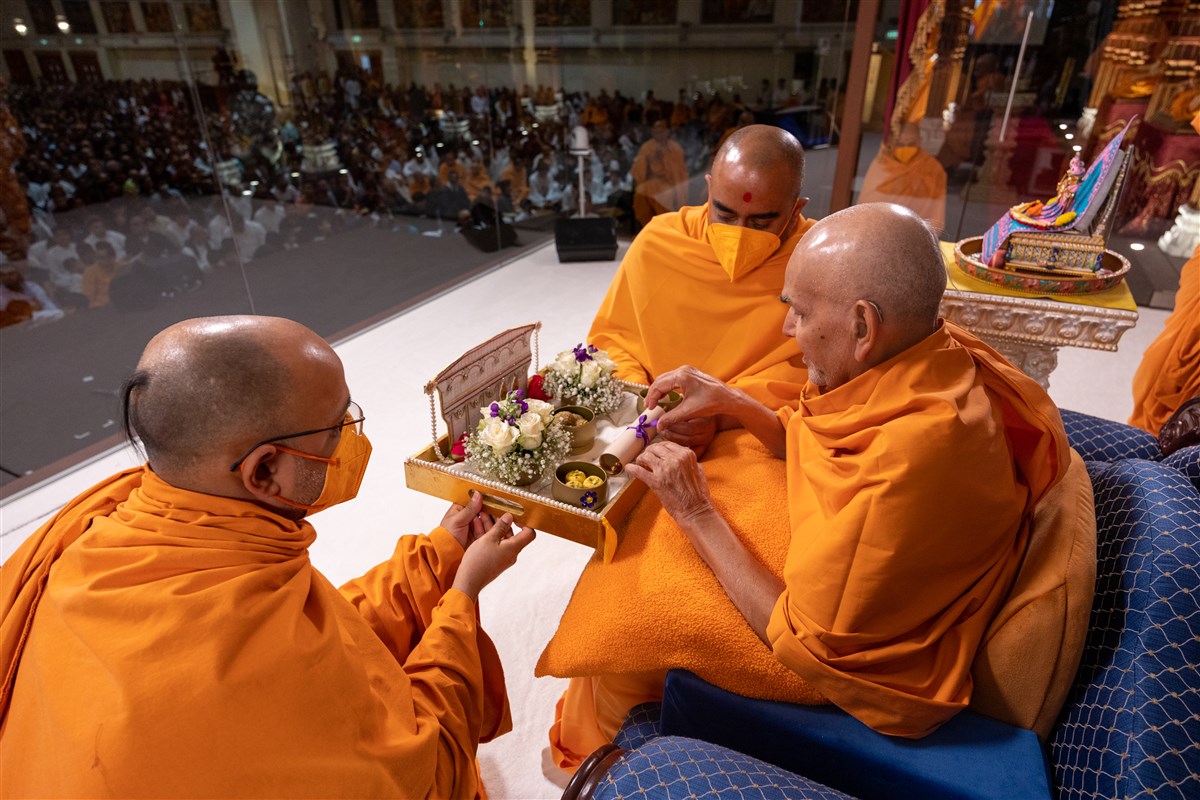 Manoharmurtidas Swami and Yagnatilakdas Swami present to Swamishri a special devotional offering from the mahilas 