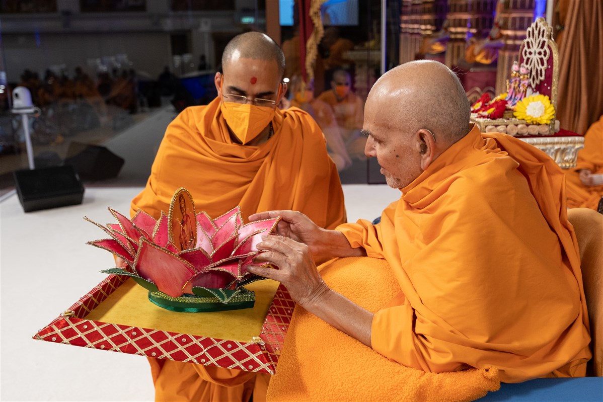 Paramtattvadas Swami presents to Swamishri a hand-crafted decorative lotus inscribed with the Sahajanand Namavali made by the mahilas