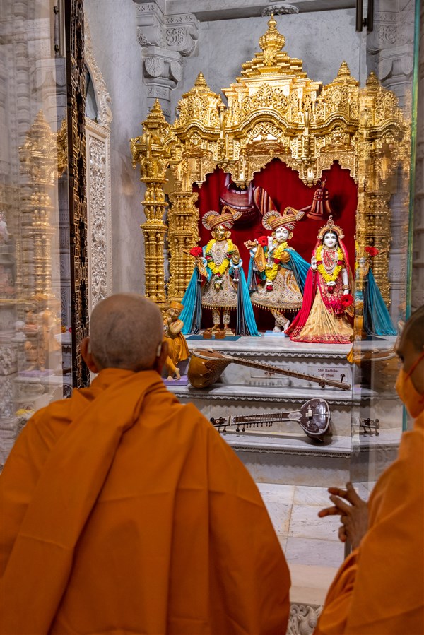 Swamishri engrossed in the darshan of Shri Harikrishna Maharaj and Shri Radha-Krishna Bhagwan