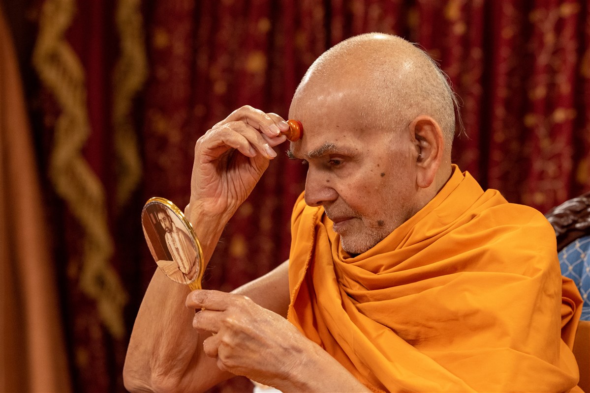 Swamishri commences his morning puja by applying a tilak-chandlo to his forehead