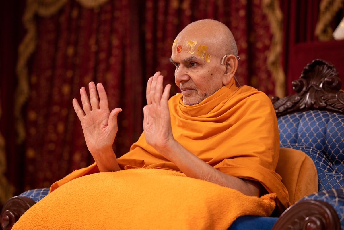 Swamishri gestures to the assembly to return to their seats