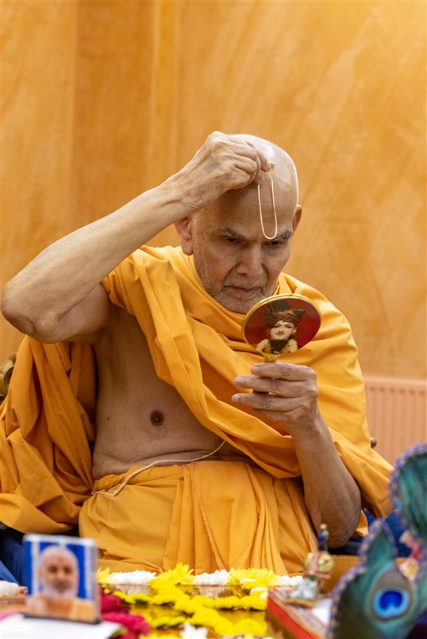 Swamishri commences his puja by applying a tilak to his forehead