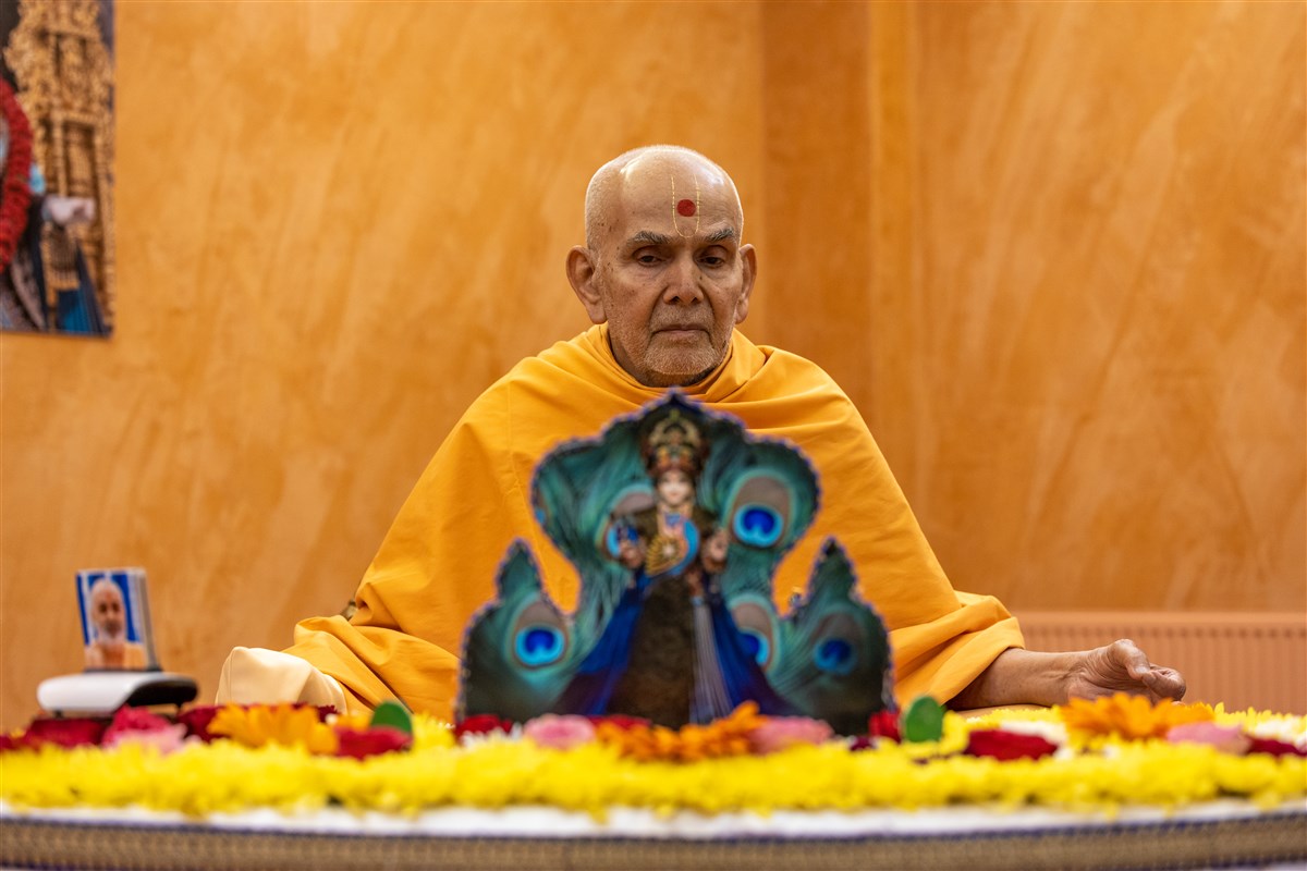 Swamishri listens attentively to the swamis while engrossed in his puja