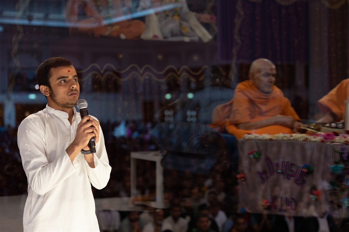 A youth recites scriptural passages related to seva in Swamishri's puja