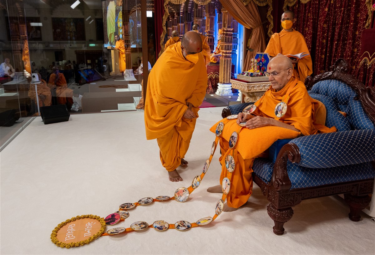 Satyavratdas Swami honours Swamishri with a decorative garland